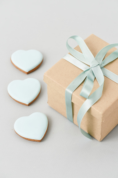 Gift is Next to Blue Heart-Shaped Gingerbread on Grey Background